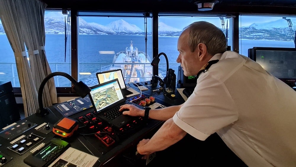 Pilot Karl Helge Haagensen at helm on vessel in Norwegian fjord, surrounded by winter landscape