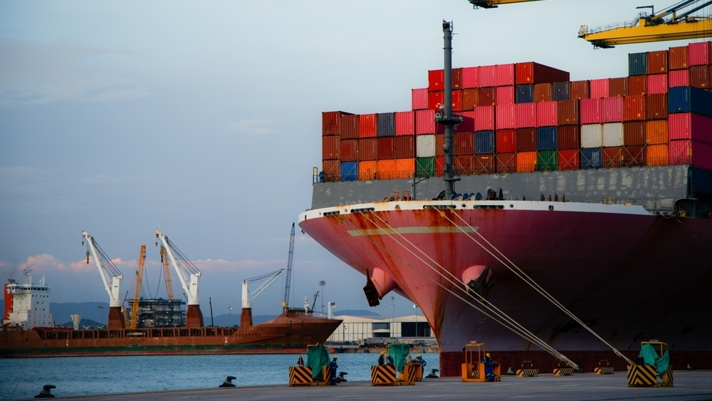 Container ship at port. Cranes and other vessels in the background.